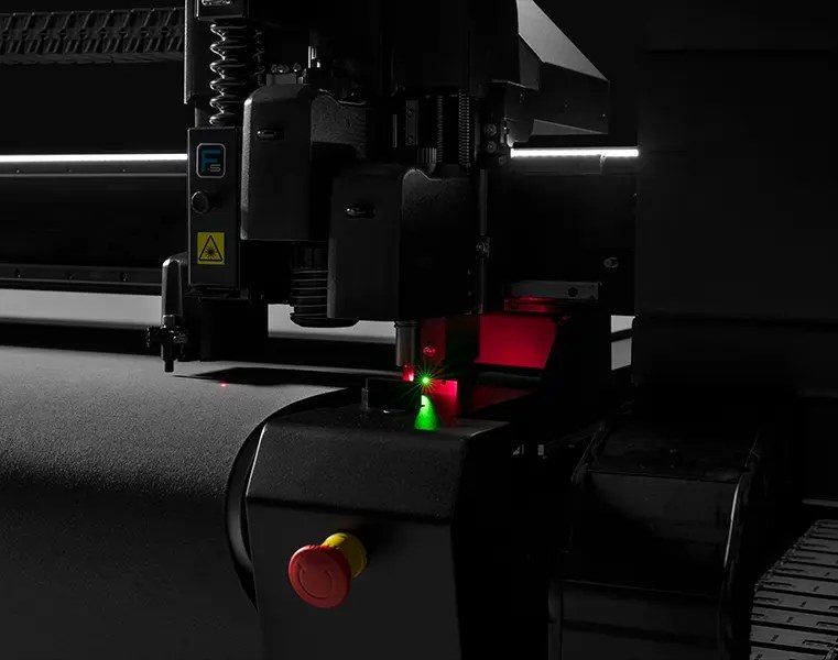 A Summa F Series cutting head at work, with the tool positioned over material on the bed